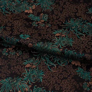 Peut inclure: Tissu noir avec un motif floral bleu sarcelle et marron. Le tissu a une apparence texturée, semblable à du brocart.