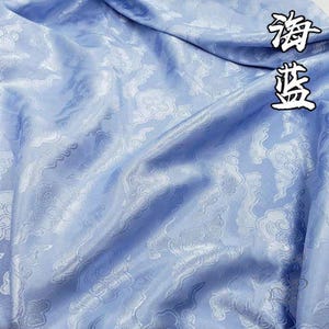May include: A light blue fabric featuring a repeating tonal pattern of stylized clouds. The material has a smooth, satin-like sheen with visible folds and drapes. The Chinese characters 海蓝 are printed in the upper right corner in black ink.