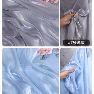 May include: Close-up of two sections of sheer fabric, one in a light gray and the other in a light blue. Both fabrics have a glossy sheen and are draped in soft folds. Pink and white flowers are placed on top of the gray fabric. The text "#7" and "#8" are visible.