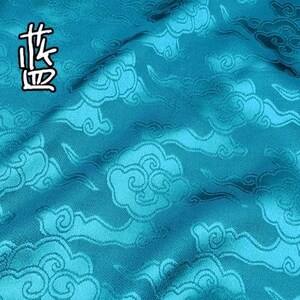 May include: A vibrant turquoise fabric featuring a repeating woven pattern of stylized clouds. The material has a subtle sheen and includes the Chinese characters 雀蓝 in the upper left corner, which translate to peacock blue.