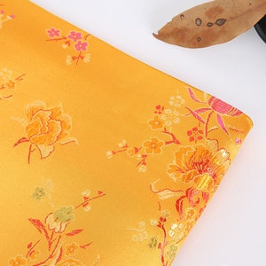 May include: A yellow fabric with a floral pattern. The fabric features pink, red, and green flowers on a yellow background.
