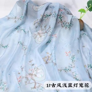 May include: A light blue fabric with a floral pattern in shades of pink, green, and brown. The fabric is draped, creating soft folds and shadows. The text "1#" and Chinese characters are visible at the bottom.