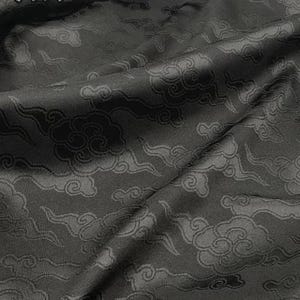 May include: A black fabric featuring a tonal jacquard pattern of stylized clouds. The fabric has a subtle sheen and folds naturally. The Chinese characters for black, 黑色, are printed in the upper left corner of the image in a light gray font.