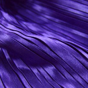 May include: Close-up of a purple pleated fabric with a smooth, silky texture.