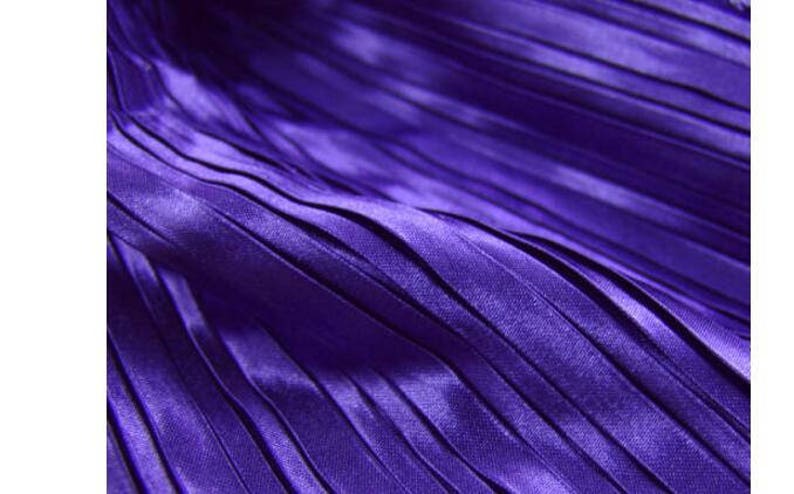 May include: Close-up of a purple pleated fabric with a smooth, silky texture.