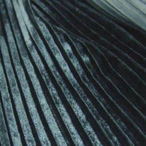 May include: Close-up of a dark blue fabric with a pleated texture. The fabric has a subtle sheen and a slightly wrinkled appearance.