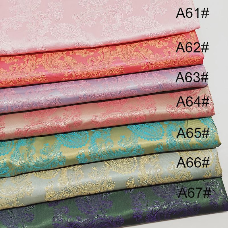 May include: A stack of colorful paisley fabric samples. The fabrics are in shades of pink, coral, lavender, teal, and green. Each fabric has a unique paisley pattern and is labeled with a code, such as A61#.