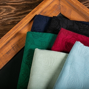 Puede incluir: Cinco muestras de tela en un marco de madera. Las muestras son de diferentes colores y patrones, incluyendo verde, azul, rojo, blanco y azul claro. La tela tiene un patrón de rosas.