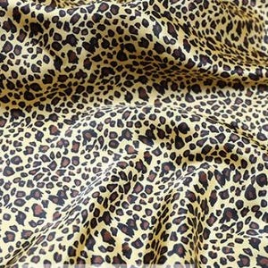 May include: Close-up of a yellow fabric with a brown leopard print pattern.