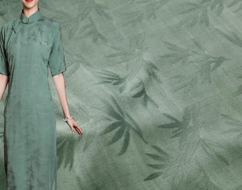 May include: A sage green fabric with a subtle embossed leaf pattern. The fabric has a soft, silky texture.