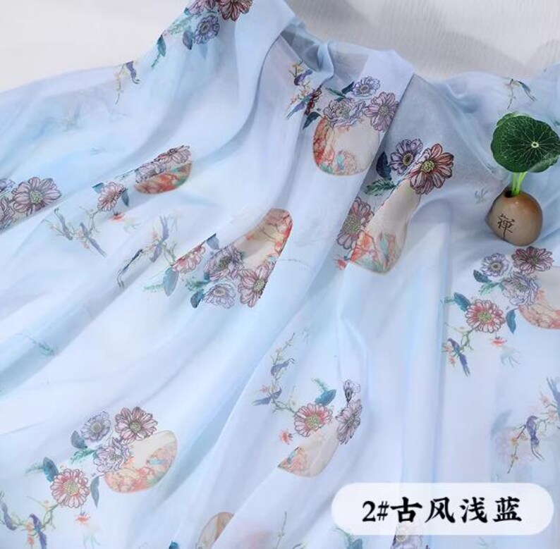 May include: Light blue fabric with a floral pattern in shades of pink, orange, and green. The fabric has a translucent quality and is draped. The text "2# ancient style light blue" is visible.
