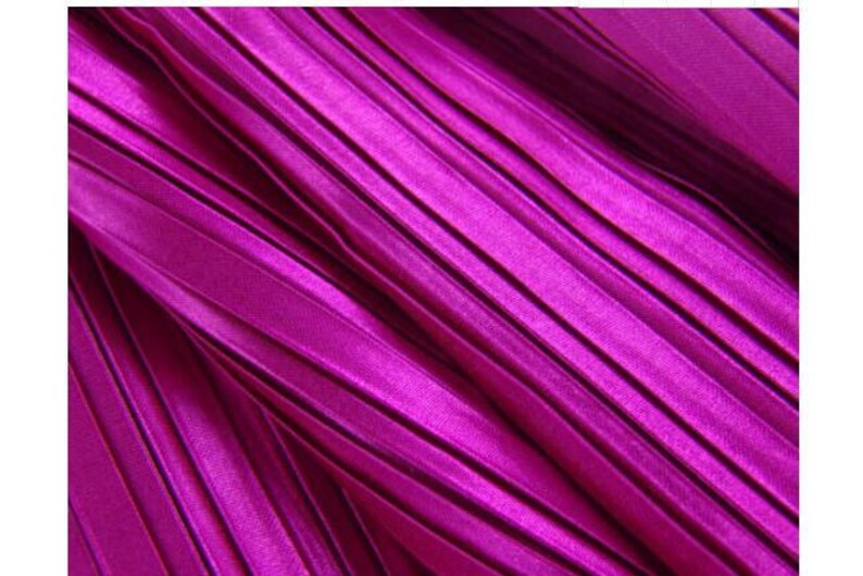 May include: Close-up of a vibrant magenta fabric with a pleated texture. The fabric has a subtle sheen and a smooth, silky feel.