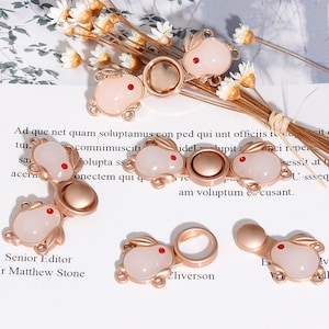 Pode incluir: Um conjunto de seis pingentes de metal dourado com um design de coelho rosa. Os pingentes têm um visual delicado e feminino e são perfeitos para adicionar um toque de fantasia a joias ou artesanato.