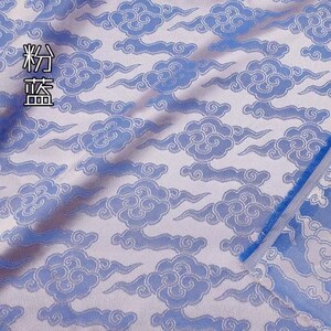 May include: A light blue fabric featuring a repeating pattern of stylized clouds in a darker blue shade. The textile has a woven texture with a visible selvage edge on the right side. The Chinese characters 粉蓝 are printed in the upper left corner.