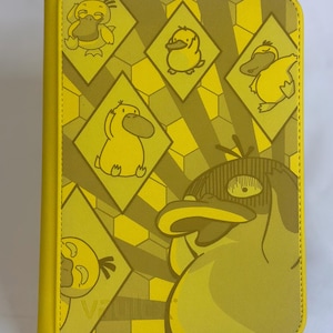 May include: Yellow notebook featuring a repeating pattern of cartoon duck characters within diamond shapes. The notebook has a solid yellow spine and a matching yellow border. The cover design includes various poses of the duck character.