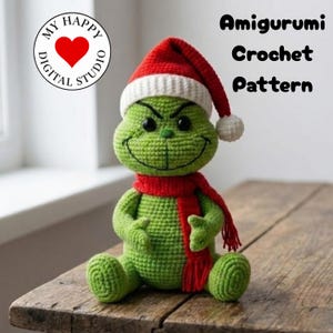 Puede incluir: Una muñeca Grinch verde tejida a ganchillo con un gorro de Papá Noel rojo y blanco y una bufanda roja. La muñeca tiene una sonrisa traviesa y está sentada sobre una superficie de madera. También incluye el texto "Amigurumi Crochet Pattern".