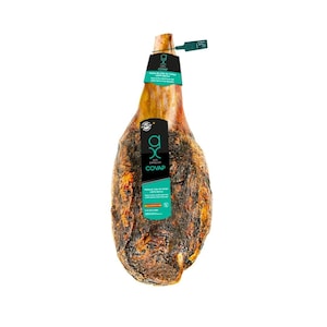 May include: A whole cured ham with a dark, textured exterior and a light-colored interior. The ham has a label with the text "COVAP" and other text in Spanish. A small tag is attached to the top of the ham.