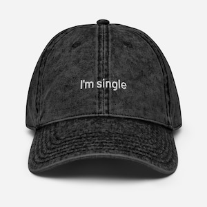Könnte beinhalten: Eine schwarze Baseballkappe im Vintage-Stil mit gebogenem Schirm. Auf der Vorderseite ist der weiße Text "I'm single" gestickt. Die Kappe hat einen Used-Look.