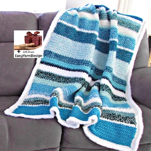 Könnte beinhalten: Eine blau-weiß gestreifte Häkeldecke mit weißem, flauschigem Rand. Die Decke ist über ein graues Sofa drapiert. Die Decke hat verschiedene Blautöne und weiße Streifen. Ein Geschenk von EasyYarnDesign.