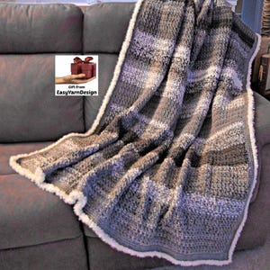 Könnte beinhalten: Eine grau-weiße Häkeldecke mit Kunstfellbesatz liegt über einem grauen Sofa. Die Decke hat ein Streifenmuster in Grau-, Weiß- und Brauntönen. Der Text "Gift from EasyYarnDesign" befindet sich in der Ecke.