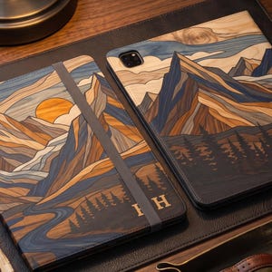 Può includere: Due custodie rettangolari per tablet con finitura effetto legno e un'illustrazione paesaggistica stampata raffigurante montagne, un sole al tramonto e una foresta. Una custodia include un cinturino elastico grigio scuro e le lettere HH dorate.