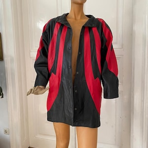 May include: A black and red leather jacket with a button-up front. The jacket features vertical red stripes on the front and sleeves. The jacket is displayed on a mannequin.