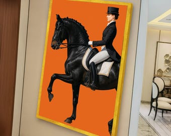 May include: A framed equestrian art print featuring a black horse and rider against an orange background. The rider is dressed in formal attire, including a top hat and riding boots. The artwork has a gold-colored frame.