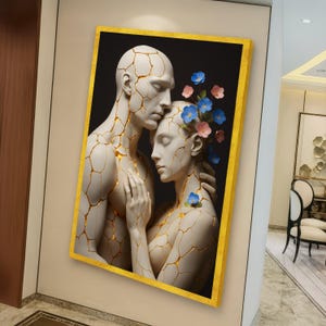 Può includere: Una stampa artistica incorniciata raffigurante una scultura di due figure che si abbracciano, con uno sfondo nero. Le figure sono bianche con crepe color oro, adornate da fiori blu e rosa. La cornice è dorata.