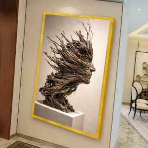 May include: A framed artwork featuring a profile of a face sculpted from intertwined branches. The sculpture is set against a neutral background and framed with a gold border. The artwork is mounted on a white pedestal.