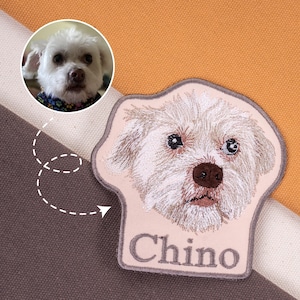 May include: Embroidered patch featuring a detailed portrait of a white dog with the name "Chino" stitched below. A smaller circular image of the dog is shown above the patch. The patch has a light pink background and a gray border.