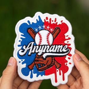 May include: Embroidered baseball patch with a white border. The design features a baseball, crossed bats, and a glove, set against a blue and red paint splatter background. The word "Anyname" is written in a script font.