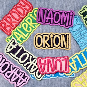 May include: A collection of embroidered name patches in various colors including red, yellow, purple, pink, and blue. Each patch features a unique name such as Brody, Naomi, Orion, Dakota, Luna, and Aaron, stitched with a bold, rounded font.