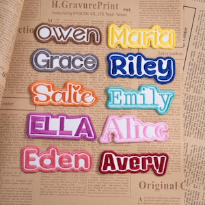 May include: A collection of colorful embroidered name patches, each with a unique font and color scheme. Names include Owen, Maria, Grace, Riley, Salie, Emily, Ella, Alice, Eden, and Avery. Perfect for personalizing clothing or accessories.