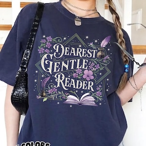 May include: Navy blue t-shirt with the text "Dearest Gentle Reader" in a floral design. The graphic includes an open book, flowers, and a quill. The shirt also has a "Comfort Colors Navy" logo.
