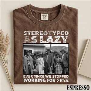 Puede incluir: Una camiseta marr&oacute;n con una fotograf&iacute;a hist&oacute;rica en blanco y negro de un grupo de personas con ropa formal. El texto STEREOTYPED AS LAZY est&aacute; impreso sobre la imagen y EVER SINCE WE STOPPED WORKING FOR FREE est&aacute; impreso debajo.