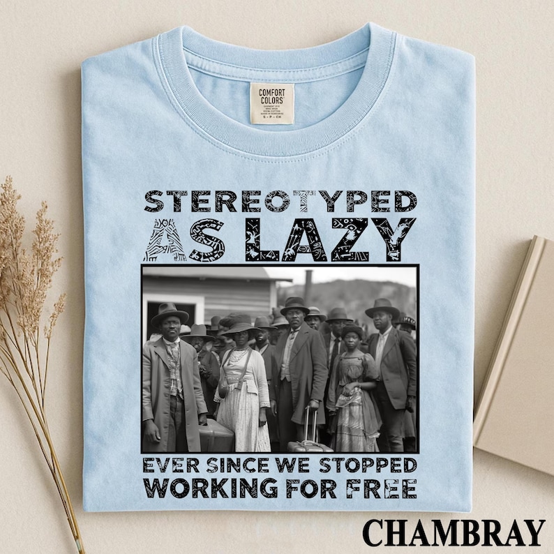 Puede incluir: Una camiseta azul claro con el texto negro STEREOTYPED AS LAZY EVER SINCE WE STOPPED WORKING FOR FREE y una fotograf&iacute;a en blanco y negro de un grupo de personas con vestimenta hist&oacute;rica frente a un edificio.