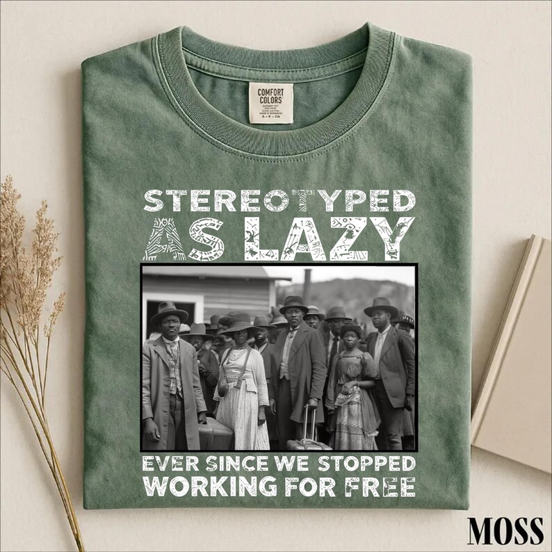 Puede incluir: Una camiseta de cuello redondo color verde musgo con una fotograf&iacute;a hist&oacute;rica en blanco y negro de un grupo de personas. Sobre la imagen, el texto dice STEREOTYPED AS LAZY, y debajo de la imagen, el texto dice EVER SINCE WE STOPPED WORKING FOR FREE.