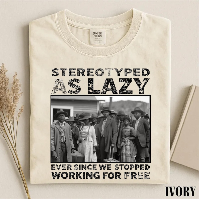 Puede incluir: Una camiseta de color marfil con un estampado gr&aacute;fico negro. El texto dice STEREOTYPED AS LAZY EVER SINCE WE STOPPED WORKING FOR FREE. Debajo de la l&iacute;nea superior de texto hay una fotograf&iacute;a en blanco y negro de un grupo de personas con ropa hist&oacute;rica.