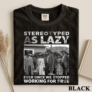 Puede incluir: Una camiseta negra de cuello redondo con una fotograf&iacute;a vintage en blanco y negro de un grupo de personas con ropa formal. El texto STEREOTYPED AS LAZY est&aacute; impreso sobre la imagen y EVER SINCE WE STOPPED WORKING FOR FREE debajo.