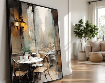 May include: Framed art print depicting a cafe scene with tables, chairs, and street lamps. The painting uses a palette of beige, brown, and white, with a black frame. The artwork evokes a sense of a European cafe.