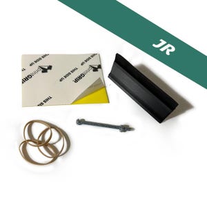 May include: An assortment of items including a black plastic piece, a bolt with a nut, several brown rubber bands, and a sticker with the text "printGRIP" and "THIS SIDE UP". The background is white with a green diagonal stripe.