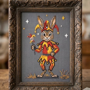 Könnte beinhalten: Kreuzstich-Kunstwerk eines Hasen als Narr, in einem rot-gelben Kostüm, der eine kleine Narrenfigur hält. Das gerahmte Stück hat einen dunkelgrauen Hintergrund und ist in einem verzierten, braunen Holzrahmen gefasst. Der Text "Velour PeachXStitch" ist zu sehen.