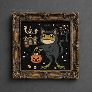 May include: A cross-stitch embroidery in an ornate bronze frame featuring a green frog wearing a dark cat costume, holding an orange jack-o'-lantern bucket. The black background includes a haunted house, a bare tree, and small candy corn icons.