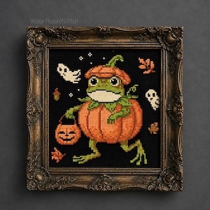 May include: A cross-stitch embroidery in an ornate bronze frame featuring a green frog wearing a pumpkin costume and hat, holding a jack-o'-lantern bucket. The black background includes white ghosts, orange leaves, and the text VelourPeachXStitch.