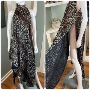 Könnte beinhalten: Ein Halfterkleid mit Leopardenmuster. Das Kleid hat einen hohen Ausschnitt und ein asymmetrisches, fließendes Design mit hohem Schlitz. Der Stoff ist eine Mischung aus Braun, Schwarz und Beige.