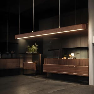 Può includere: Una lampada a sospensione rettangolare in legno con una striscia LED integrata che emette una luce calda. La lampada è sospesa al soffitto. L'interno presenta mobili in legno scuro e un design moderno.