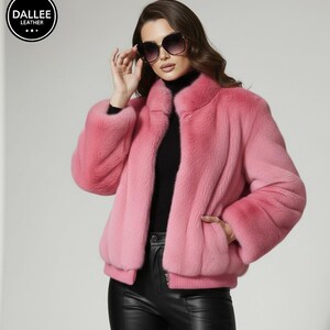 Peut inclure: Une veste en fausse fourrure rose vif avec un col montant, des manches longues et un ourlet côtelé. La veste est portée sur un pull à col roulé noir et associée à un pantalon en cuir noir. Elle présente une fermeture éclair frontale.