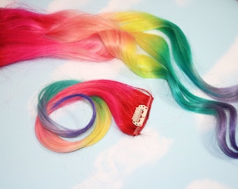 May include: Two sets of rainbow colored clip-in hair extensions. The first set is pink, orange, yellow, green, and purple. The second set is green, yellow, orange, pink, and purple.