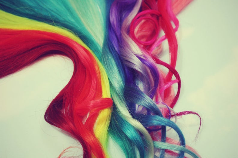 K&ouml;nnte beinhalten: Nahaufnahme einer regenbogenfarbenen Haarverl&auml;ngerung. Das Haar ist gewellt und in einem kaskadierenden Muster angeordnet, mit Str&auml;hnen in Rot, Orange, Gelb, Gr&uuml;n, Blau, Indigo und Violett.