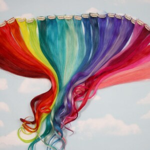 K&ouml;nnte beinhalten: Ein Set regenbogenfarbener Clip-in-Haarverl&auml;ngerungen. Die Extensions sind in einem Regenbogenmuster angeordnet, mit Rot, Orange, Gelb, Gr&uuml;n, Blau, Indigo und Violett.